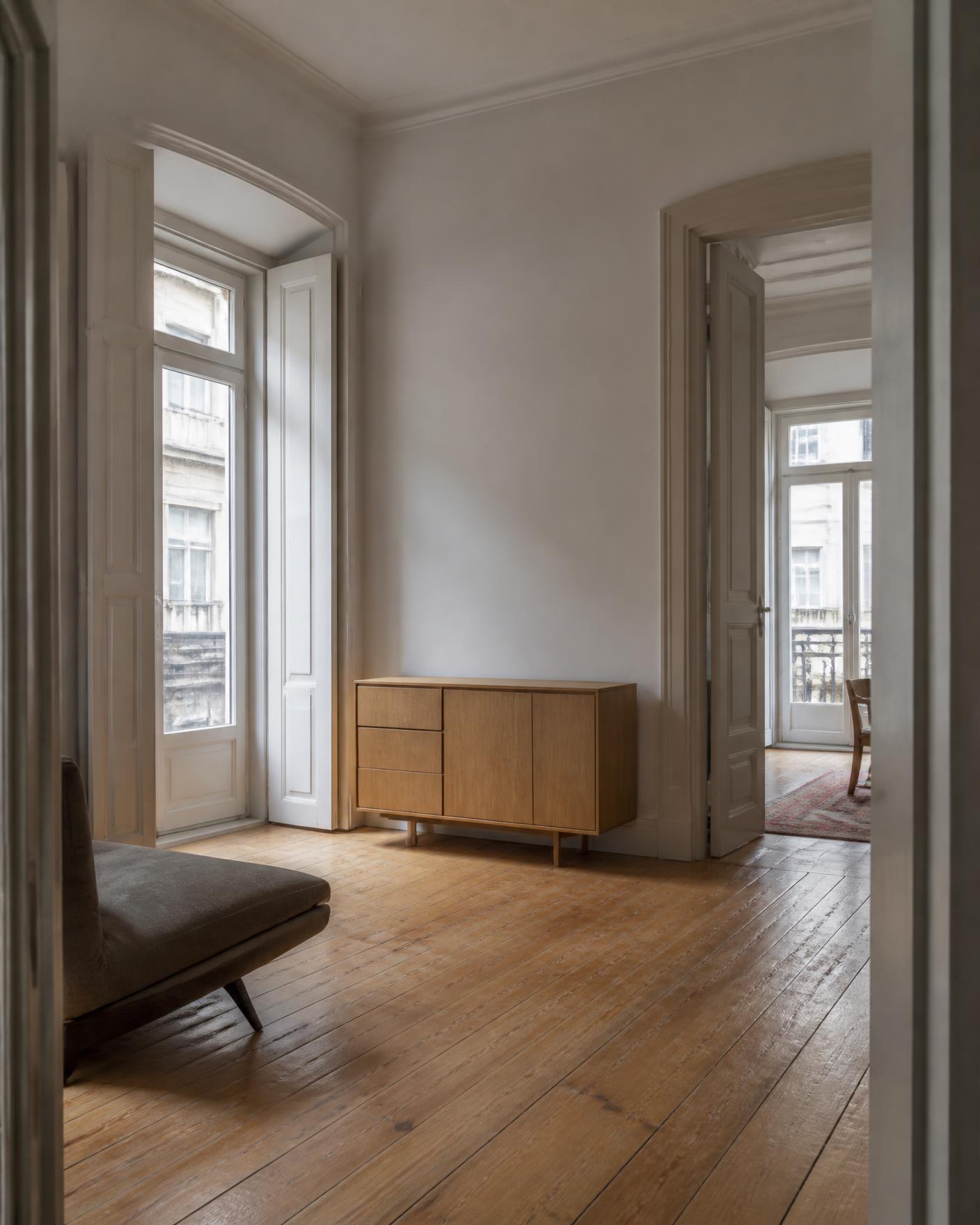 Interior de apartamento pombalino reabilitado com soalho original e mobiliário em carvalho