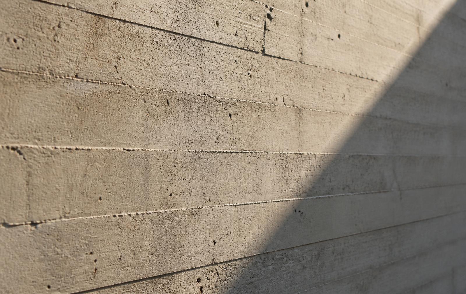 Textura de betão aparente com marcas de cofragem e sombra diagonal